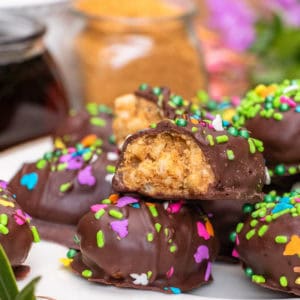 Platter of chocolate-covered peanut butter eggs covered in rainbow sprinkles.