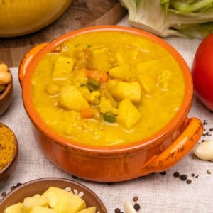 A bowl of golden coconut soup surrounded by ingredients.